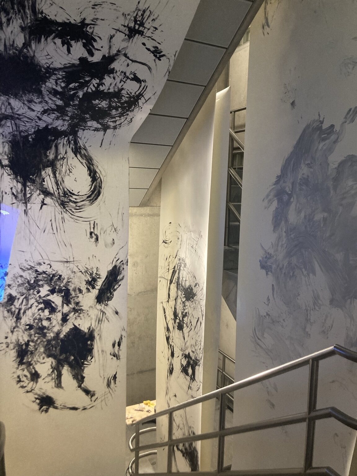 Painted traces rising through an interior beside a stair rail